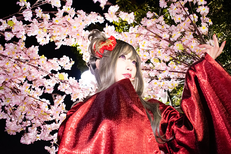 街灯に照らされた夜桜と赤い着物の女性の写真。