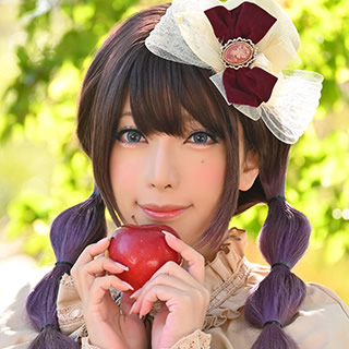 木立の下、真っ赤なリンゴを手にポーズを決める女性の写真。