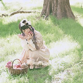 木下の座り左手にリンゴを持って目をつぶる女性の写真。