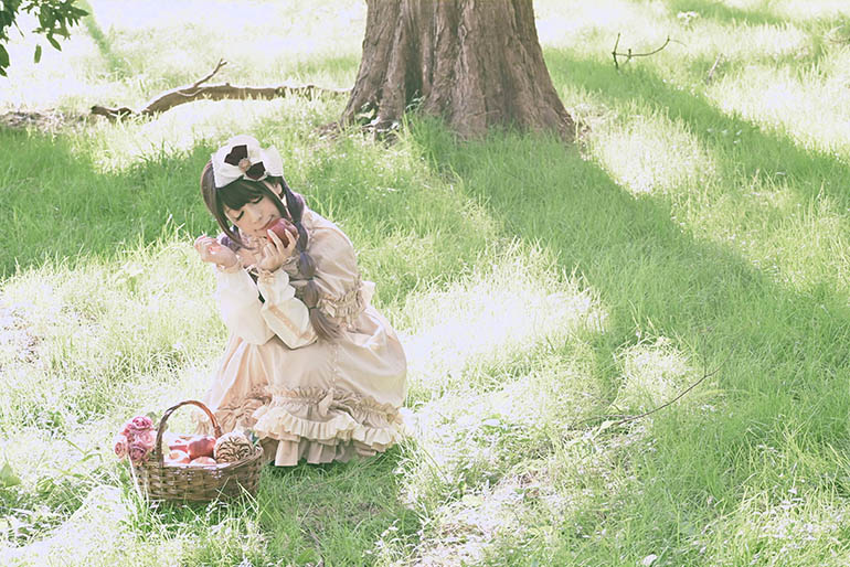 木下の座り左手にリンゴを持って目をつぶる女性の写真。